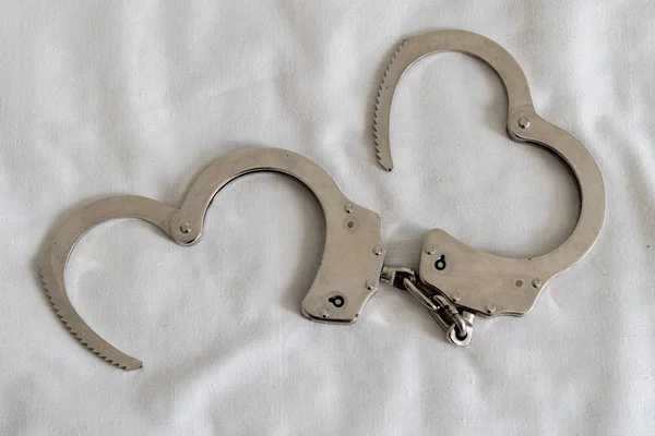 Beyaz kalp şeklinde arka planı olan kelepçeler.