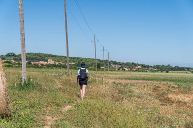 Girona, Katalonya, İspanya 'da çember saman balyalarıyla tarlalar arasında yürüyen bir kadın yürüyüşçü..
