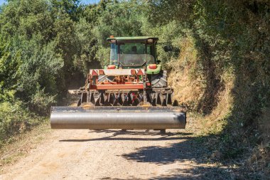 Toprak yolda giden bir traktör..