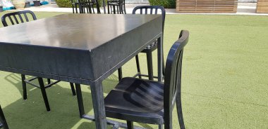 Siyah yüksek sandalye ve bir tablo g yeşil atrificial çimenlerin üzerinde