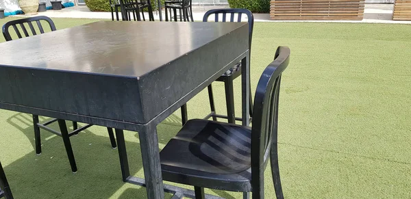 black high chairs and a table on green atrificial grass in the g