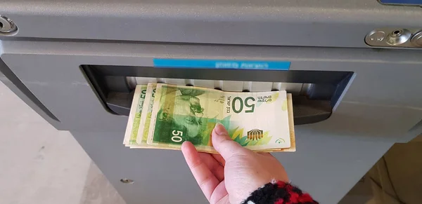 Oude vrouw trekt bankbiljetten Israëlische sikkels uit contanten terugtrekking m Stockfoto
