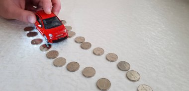 Rishon lezion, İsrail - 2 Mart 2019: bir adam ile onun parmak kırmızı fiat 500 abarth oyuncak beyaz arka plan üzerinde bir İsrail Şekeli sikkelerin yapılan yol çizgi üzerinde taşır