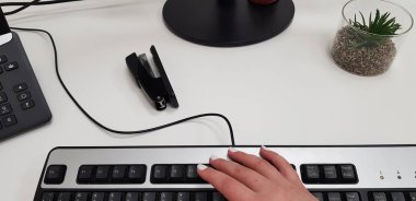 el üstünde siyah bilgisayar klavye ofis telefon stepler ve beyaz masa şeffaf kutusunda küçük yeşil bitki