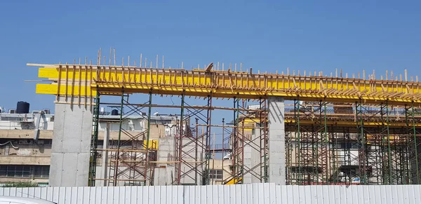 construction site over a fence with concrete columns metal beams and wooden scaffolding for future building