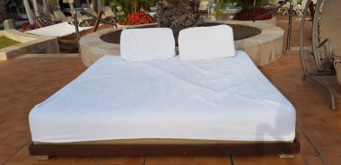 Bronzlaşma ve dinlenmek için rahat bir yatak yakın yukarı beyaz minder bir sallanan sandalye yakınında otel bahçesinde boş kalmak