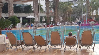 bir adam suya hiç kimse ile egzotik otel mavi yüzme havuzu bakarak sallanan chait onun sırtıyla oturan