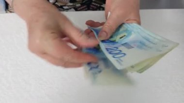 beyaz masa üzerinde şekel banknotlar sayma kıdemli kadın