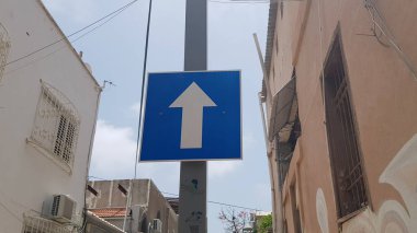 ileri ok yol işareti mavi ve beyaz renk sokakta kutup asılı