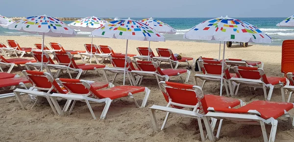 colorful sun shadow umbrellas and orange chairs on the beach near the sea