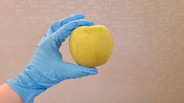 Elindeki yeşil taze elma Cerrahi kauçuk eldiven