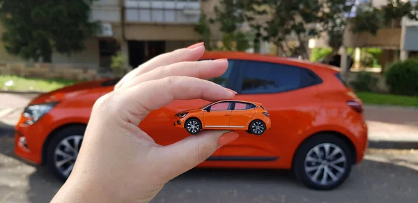 Woman Holds Small Orange Car Model Real Car Same Color — Stock Photo, Image