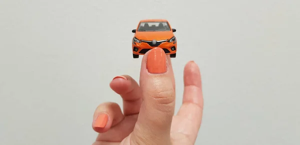 Mão Feminina Segura Pequeno Brinquedo Carro Metal Laranja Fundo Isolado — Fotografia de Stock