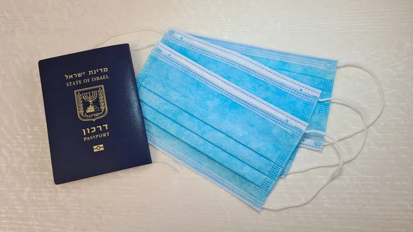 passport of israel on white table near three blue face protection masks