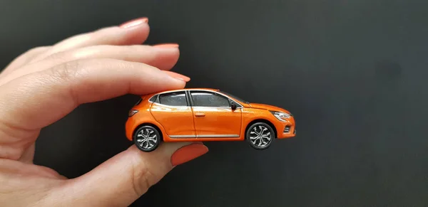 Metalen Oranje Auto Speelgoed Vrouwelijke Vingers Zwarte Achtergrond Stockafbeelding