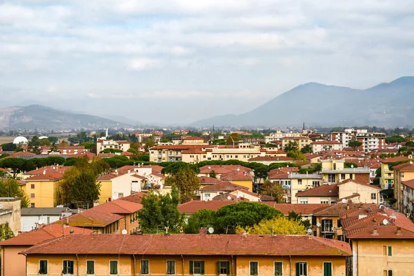 Pisa, Toskana/İtalya - 25.10.2018: Ünlü Eğik Kule'den Pisa'nın panoramik manzarası. İtalyan yaşam evleri, kafeler, kiliseler, sokaklar. Ufukta dağlar var. Bulutlu gökyüzü.