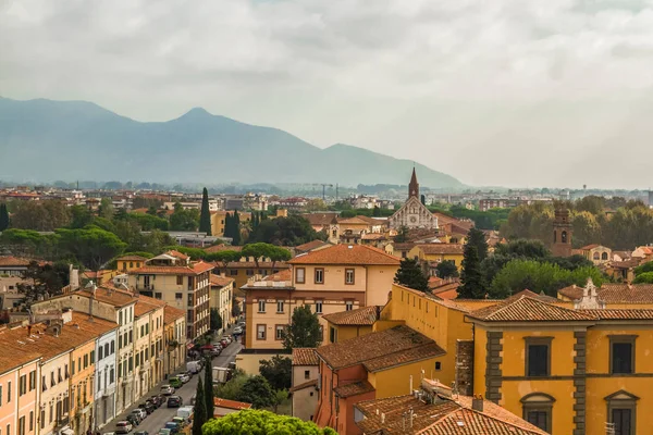 Pisa, Toskana/İtalya - 25.10.2018: Ünlü Eğik Kule'den Pisa'nın panoramik manzarası. İtalyan yaşam evleri, kafeler, kiliseler, sokaklar. Ufukta dağlar var. Bulutlu gökyüzü.
