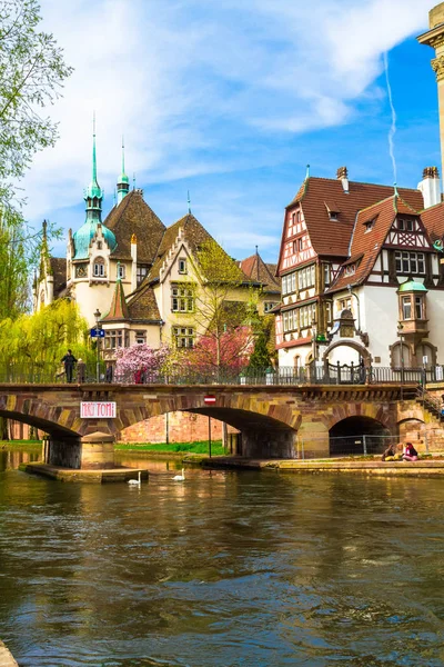Strazburg, Alsace/Fransa - 01.04.2019: Ill nehri kıyısında lisenin inşası. Söğüt, kiraz ve elma ağaçları, eski kemer köprü, yarı ahşap bina ile Bahçe. Parlak güneşli bir gün