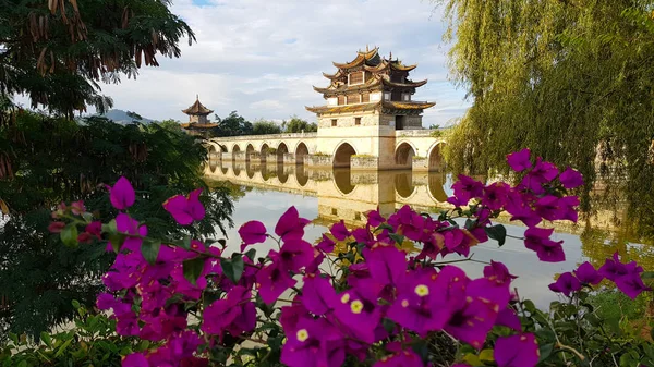 Old chinese bridge and bougainvillea. The ancient Shuanglong Bridge (Seventeen Span Bridge) near Jianshui, Yunnan, China