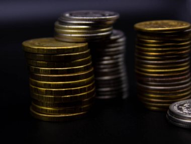 Sikkeler kavram duvar ve güçlü para siyah arka plan üzerinde yığını.