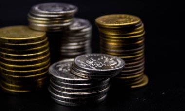 Sikkeler kavram duvar ve güçlü para siyah arka plan üzerinde yığını.