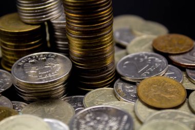 Sikkeler kavram duvar ve güçlü para siyah arka plan üzerinde yığını.