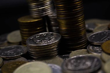 Sikkeler kavram duvar ve güçlü para siyah arka plan üzerinde yığını.