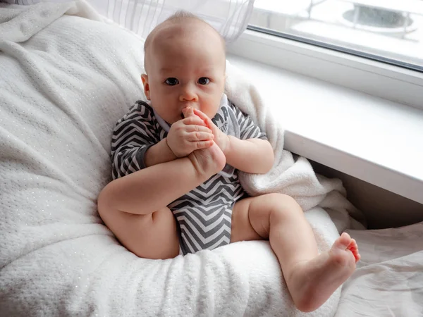 Close up ritratto di carino bambino ragazzo sdraiato su una coperta succhiare le dita dei piedi, piedi, piede, misto metà razza est asiatico caucasico ragazzo guardando felice la fotocamera . — Foto Stock