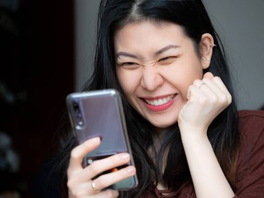 Son derece heyecanlı genç Asyalı güzel kadın tarafından mobil app satış mesaj smartphone, holding, cep cep telefonu sevinçle çığlık seyir euphoric kız kazanan bakarak hayran. Büyük gözleri