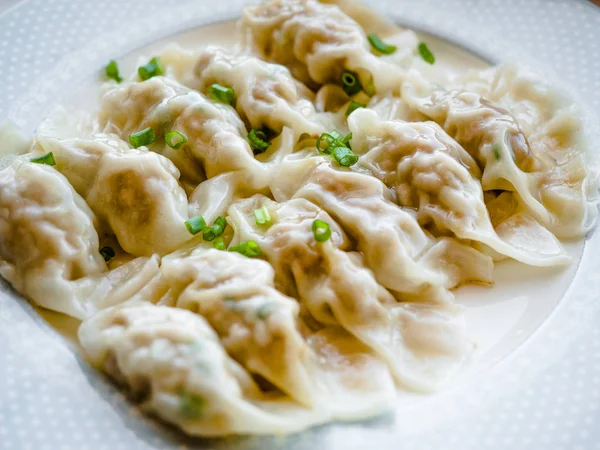 Close up frescos bolinhos de gyoza cozidos com vapores quentes, bolinhos asiáticos Gyozas potstickers fritos sobre placa preta, cozinhar bolinhos de gyoza, potstickers, comida japonesa — Fotografia de Stock