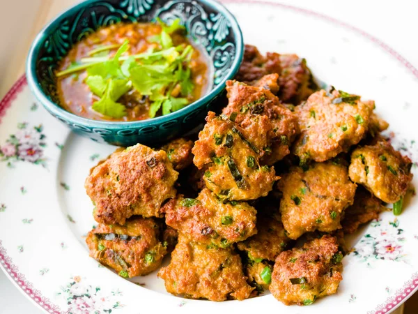 Derin kızarmış balık mantı, salatalık dilimleri olan turşu ile Tay balık köftesi derin kızarmış fesleğen yaprakları ile süslenmiş hizmet vermektedir