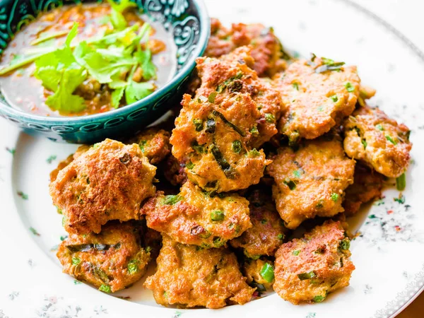 Derin kızarmış balık mantı, salatalık dilimleri olan turşu ile Tay balık köftesi derin kızarmış fesleğen yaprakları ile süslenmiş hizmet vermektedir