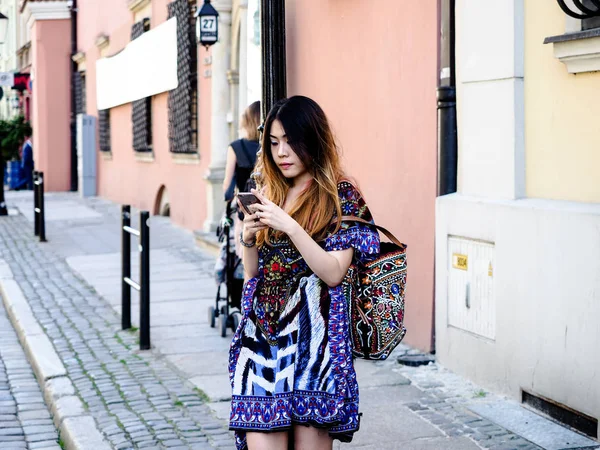 An Asian young woman looking, using her mobile phone to find a way how to go, losting in a city, check email, message, social media. travel alone in Europe.