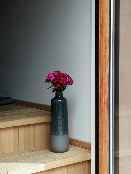 Аромат красных и розовых цветов в вазе, стоящей на яркой деревянной лестнице. японский, китайский стиль — стоковое фото