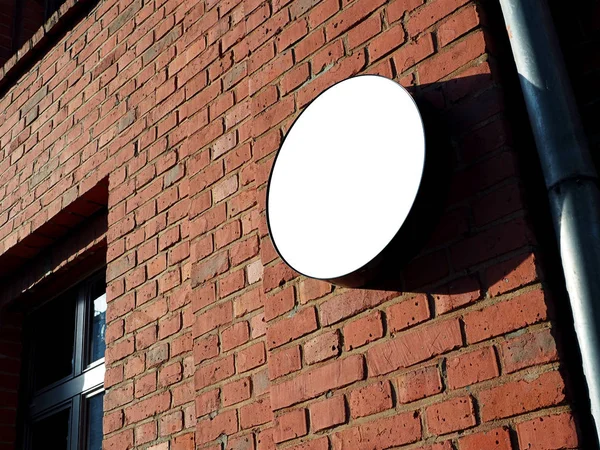 招牌侧视图的空白色与阴影模拟标牌在一个黑色的框架与旧红砖城墙背景显示外部。非常现代的形状 图库照片