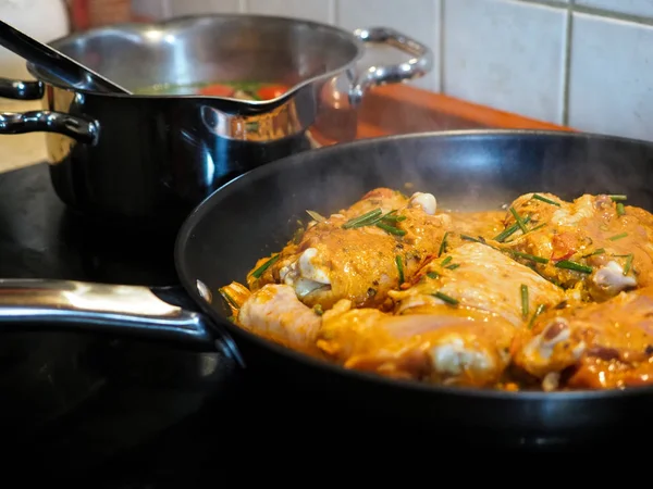 Frango fumegante com caril indiano na frigideira. Conceito de cozinha, pedaços de filé de frango em ingredientes de molho de curry em uma panela com a moderna mesa de cozinha vista lateral close-up horizontal . — Fotografia de Stock