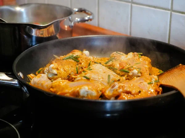 Frango fumegante com caril indiano na frigideira. Conceito de cozinha, pedaços de filé de frango em ingredientes de molho de curry em uma panela com a moderna mesa de cozinha vista lateral close-up horizontal . — Fotografia de Stock