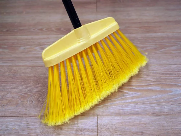 Overhead view of long handle broom with a hardwood floor, yellow broom for cleaning. — Stock Photo, Image