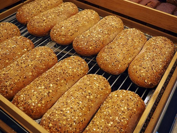 Bread with sunflower seeds from the bakery store, horizontal overhead view. A few of bread in a wooden basket, fresh and fragrant, tasty warm, crusty French bread — Stock Photo, Image