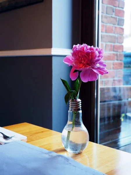 Маленький городской букет розовых цветов в вазе из стеклянной лампочки, стоящей на ярком деревянном столе японского . — стоковое фото
