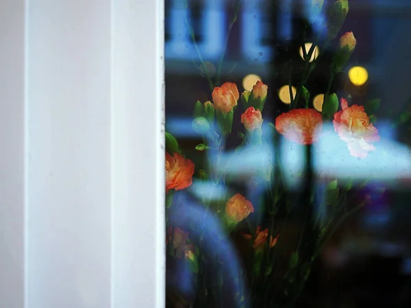 Glass window with reflection of view from a street outside the restaurant and coffee shop, and flowers for decoration.