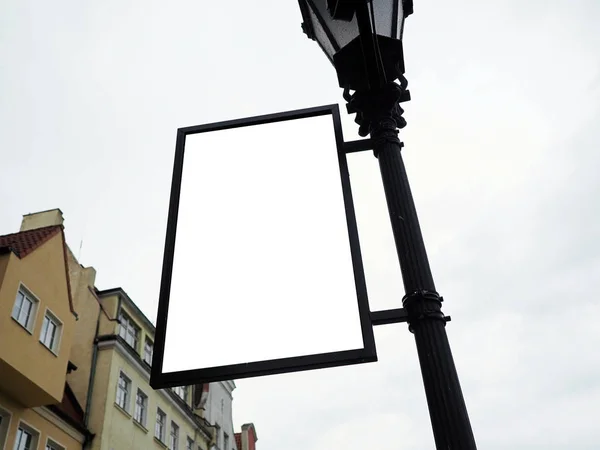 Jelzőtábla oldalnézetből üres fehér kigúnyolják jelzések egy fekete keretben a régi város falán háttér kijelző külső. Modern stílus, művészi Fémkovácsolás díszítéssel a városi utcai lámpán — Stock Fotó