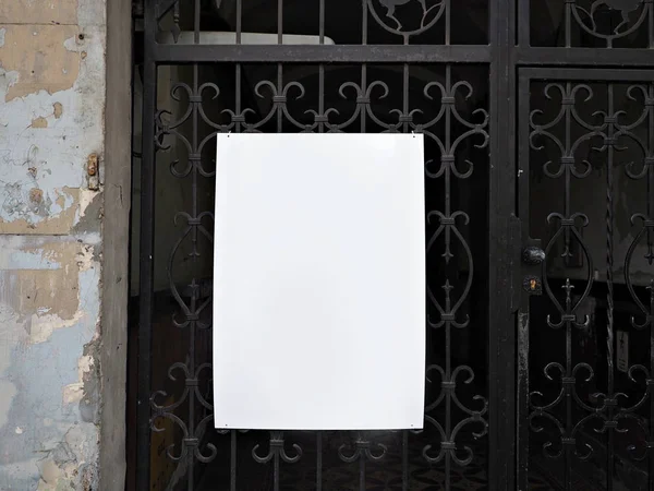 stock image Poster, announcement,  empty blank white mock up, information board, on an old ruined, poor dirty wall and metal gate, block, display exterior.