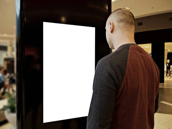 Un homme avec des médias numériques vierge écran noir et blanc panneau moderne, enseigne pour la conception de la publicité dans un centre commercial, galerie. Maquette, maquette, maquette avec fond flou, kiosque numérique . — Photo