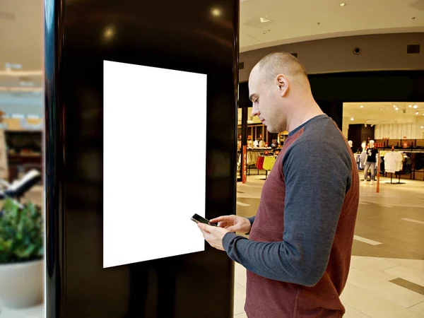 Egy férfi a digitális média üres fekete-fehér képernyő modern panel, jelzőtábla reklám design egy bevásárló központ, Galéria. Mintadarab, modell-up, gúnyolódott, homályos háttérrel, digitális kioszk. — Stock Fotó