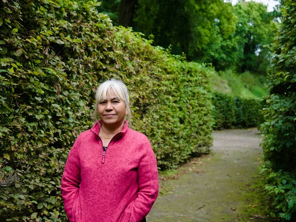 60 years old age Asian Thai woman traveling in Europe old beautiful city with garden view on background for holiday.