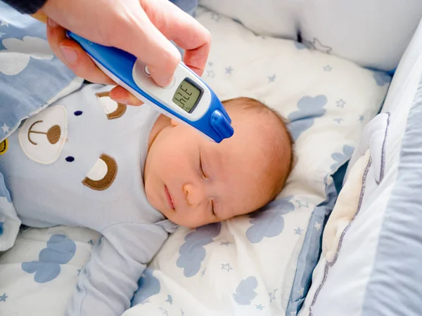 Mère, le parent vérifie la température du bébé malade, enfant malade avec une forte fièvre couché au lit, thermomètre de maintien, Compresser le coussin de refroidissement sur le front — Photo