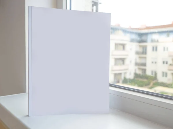 Κενό κενό βιβλίο λευκών περιοδικών στο λευκό τραπέζι δίπλα στο παράθυρο, για κάλυψη σχεδίασης ή χαρτοφυλάκιο εταιρικού προφίλ. — Φωτογραφία Αρχείου