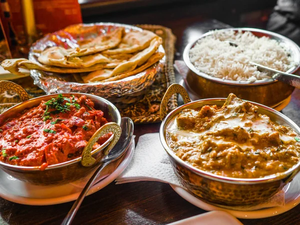 Indian Food or Indian Curry in a copper brass serving oriental bowl, pieces of chicken fillet in curry sauce ingredients in a pan with the old table side view close-up, Set of Indian food.