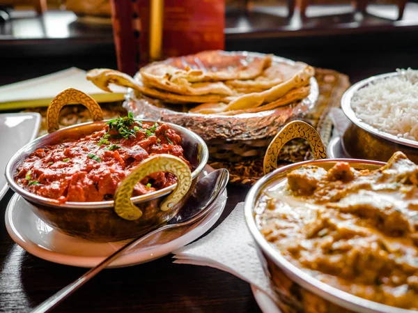 Indian Food or Indian Curry in a copper brass serving oriental bowl, pieces of chicken fillet in curry sauce ingredients in a pan with the old table side view close-up, Set of Indian food.